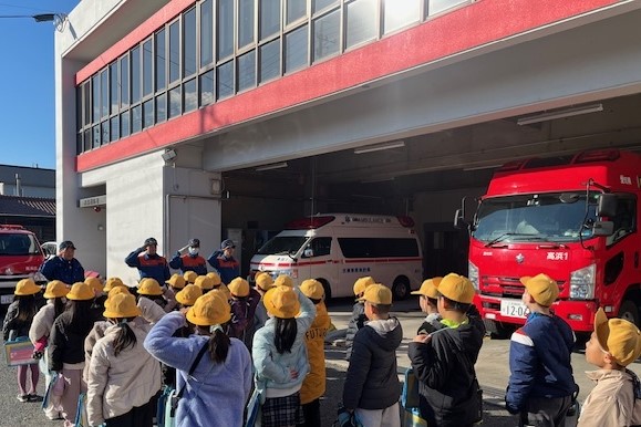 敬礼している消防士と小学生