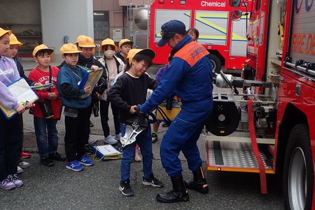 消防士が使う資器材の重さを体験する小学生
